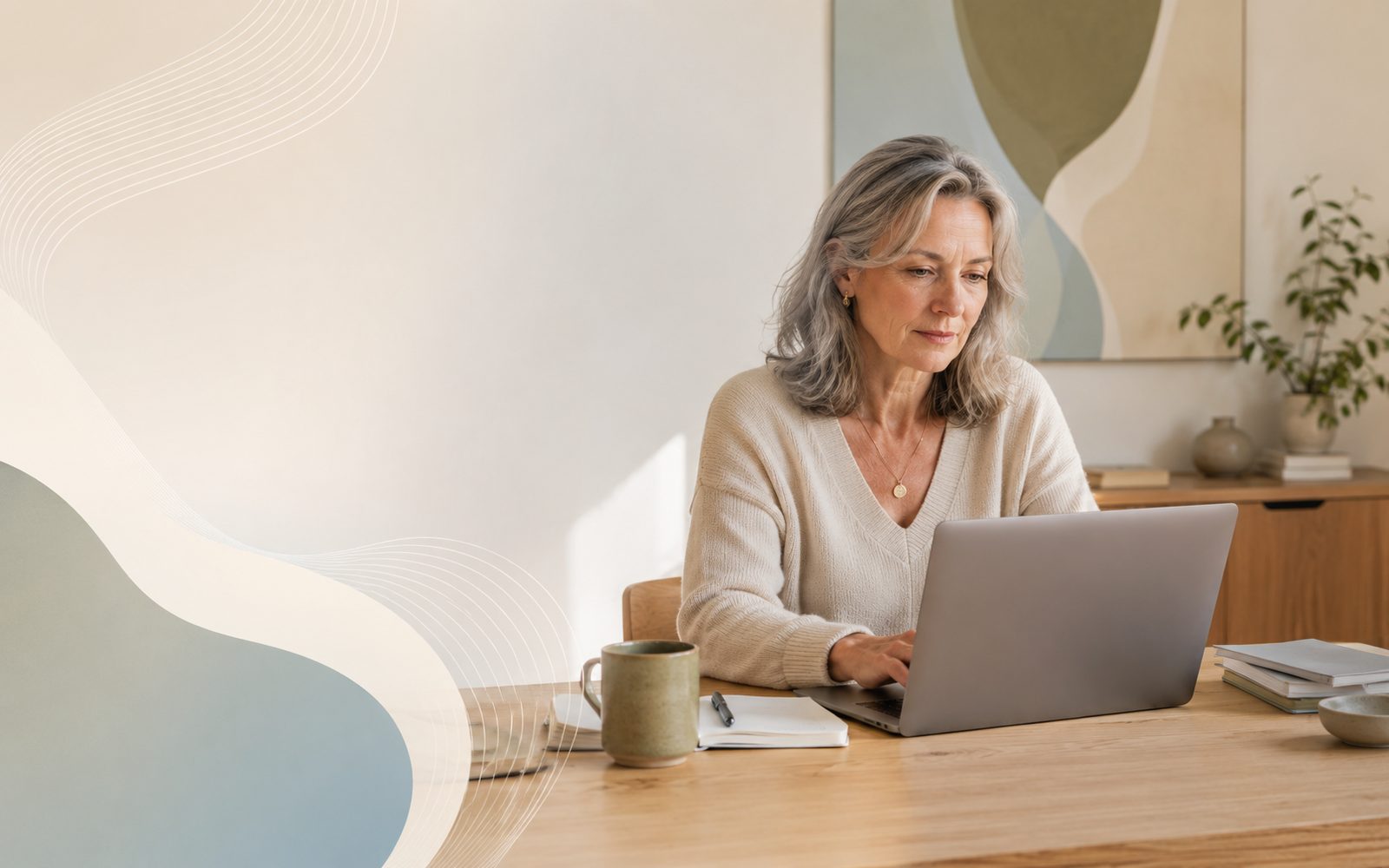 Person over 50 working thoughtfully at a laptop in a modern workspace